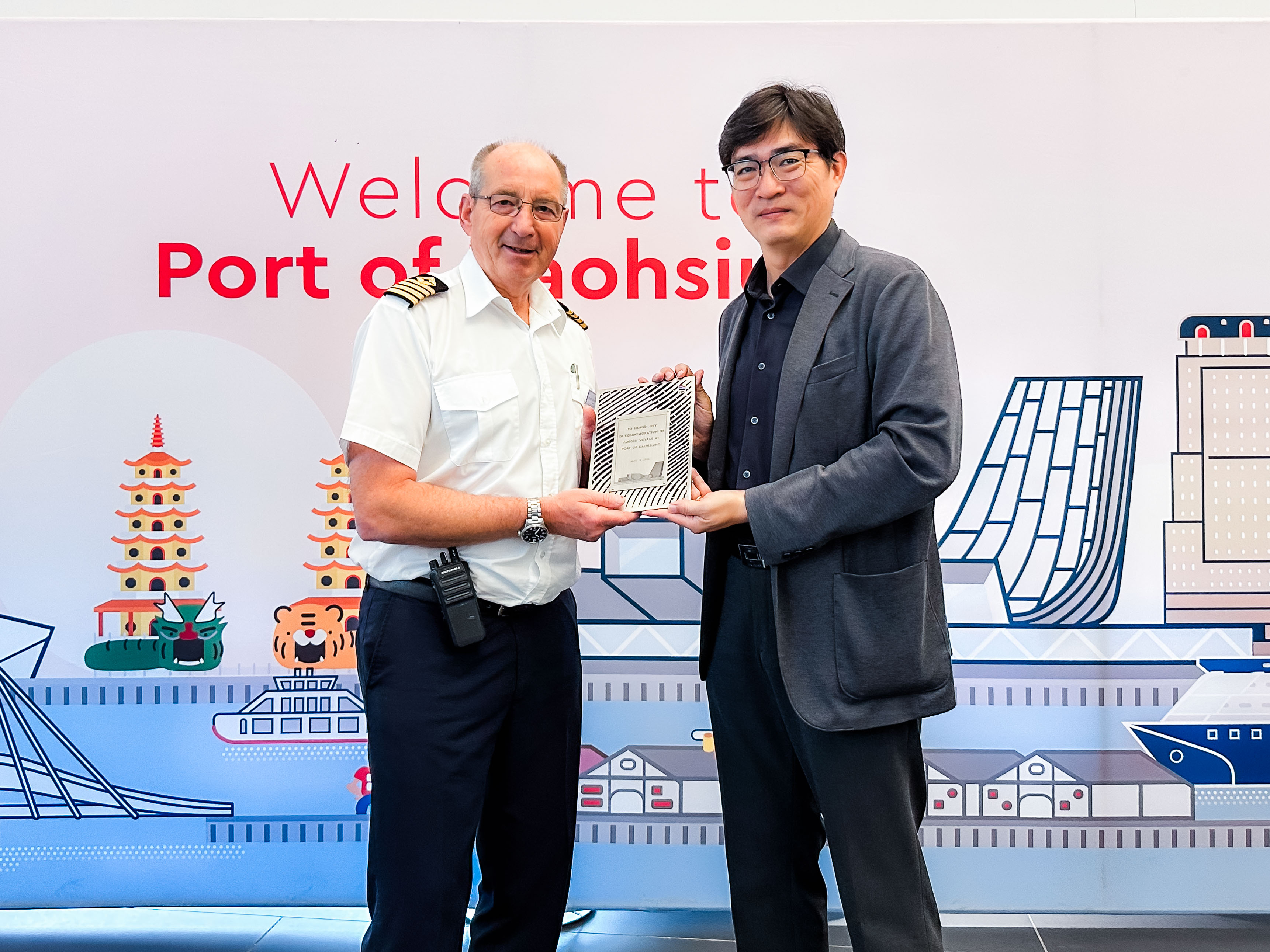 圖五：高雄港務分公司蔡建郎處長(右)代表致贈首航紀念牌予卡莉多麗「島嶼天空」（ISLAND SKY）船長(左)。
